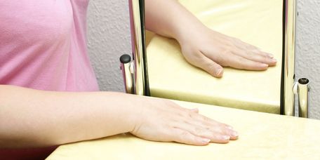Spiegeltherapie Patienten betrachtet Hand im Spiegel bei der Spiegeltherapie