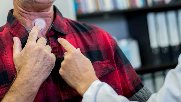 Arzt prüft Tracheostoma eines Patienten