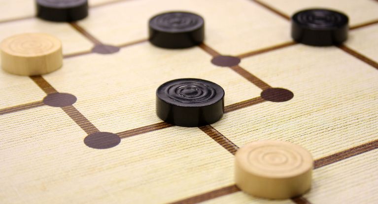 schwarze und weiße Mühlesteine auf einem Spielbrett