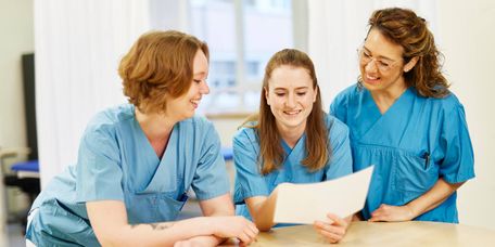 Teamarbeit in der Pflege Drei weibliche Pflegekräfte besprechen die Übergabe