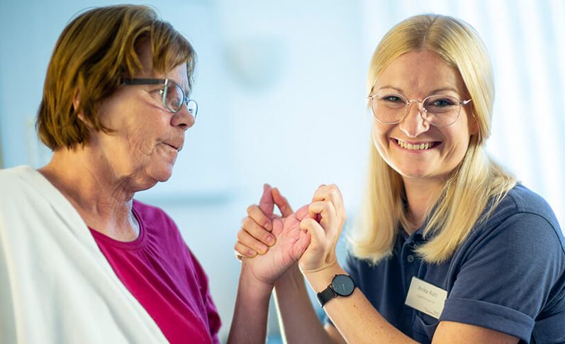 Therapeutin behandelt Hand einer Patienin