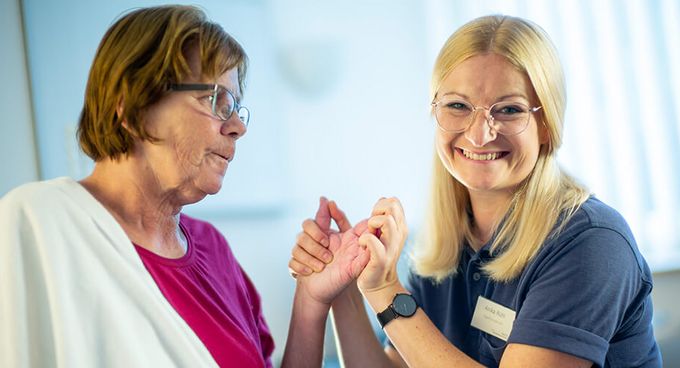 Therapeutin behandelt Hand einer Patienin