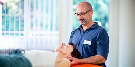 Therapeut massiert Fuß eines Patienten