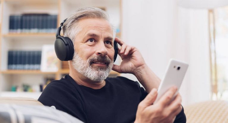 Mittealter Mann mit Kopfhörer hört Musik auf dem Smartphone