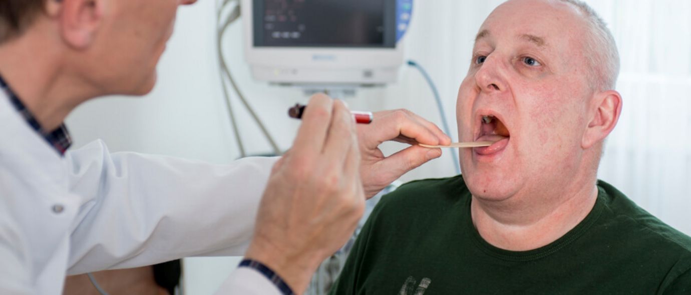 Arzt untersucht Rachen eines Patienten