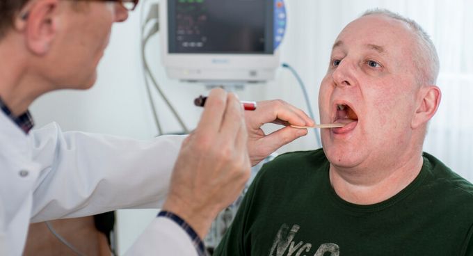 Arzt untersucht Rachen eines Patienten