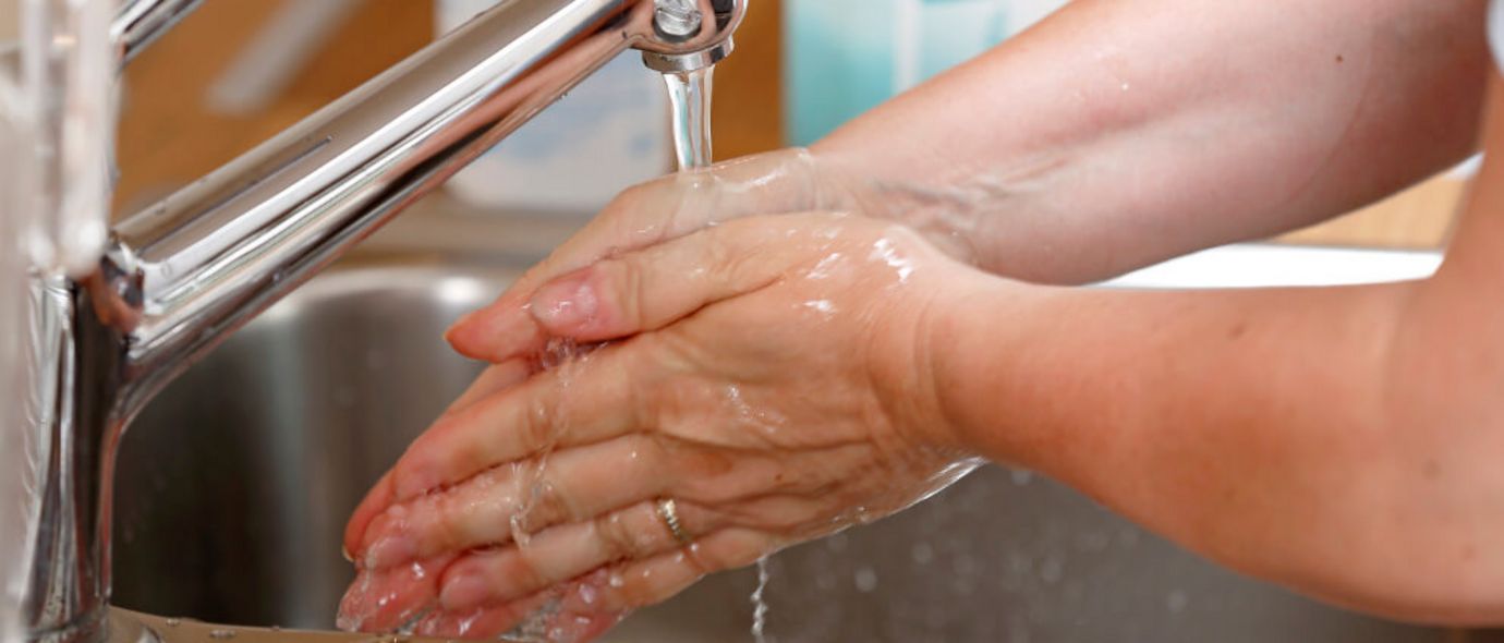 Mensch wäscht sich Hände unter einem laufenden Wasserhahn