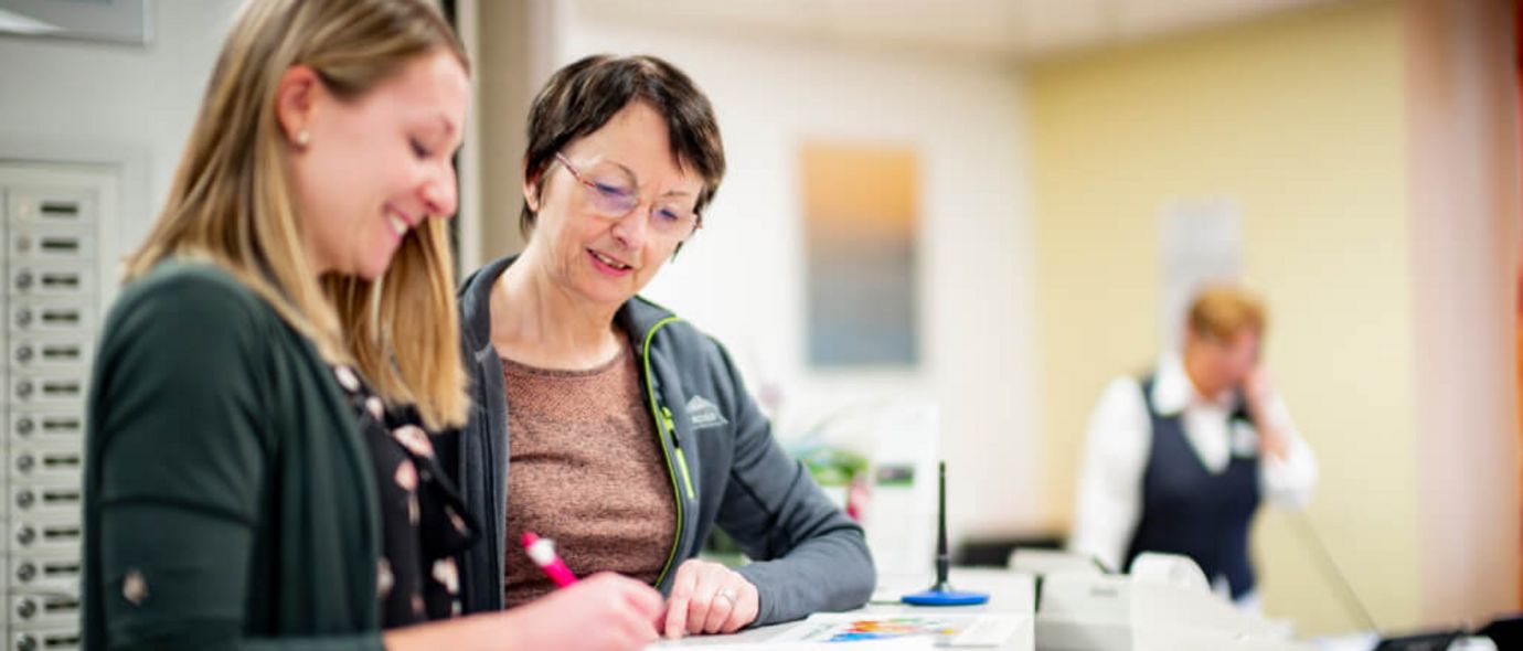 Patientinnen tragen sich an der Rezeption in eine Liste ein