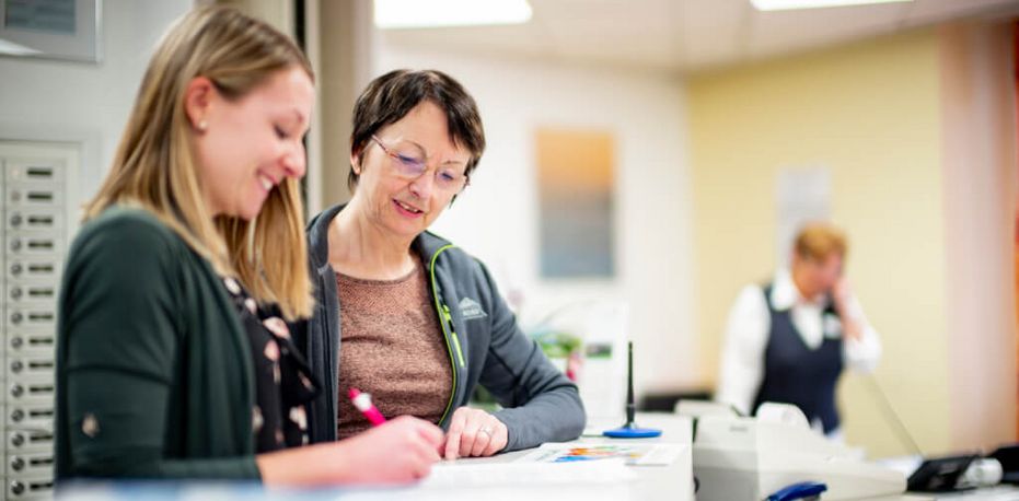 Patientinnen tragen sich an der Rezeption in eine Liste ein