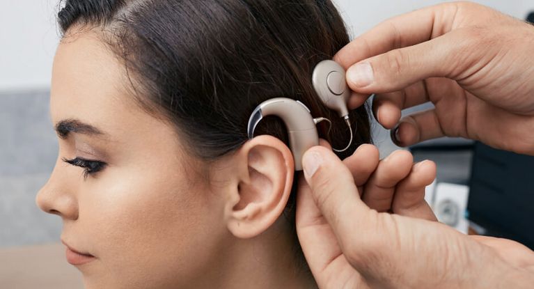 Fachkraft stellt Cochlea Implantat am Kopf einer Patientin ein