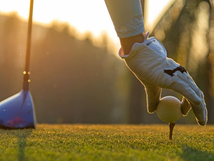 Golfspielerin legt Ball auf den Boden