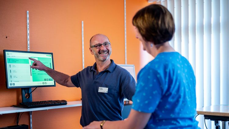 Thrapeut erklärt Patientin Ergebnisse auf einem Bildschirm